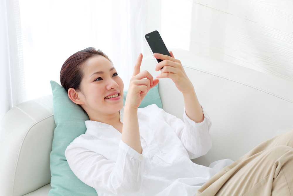 くつろぎながらスマホを見る女性